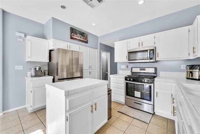 kitchen with light tile patterned flooring, white cabinets, stainless steel appliances, and a kitchen island