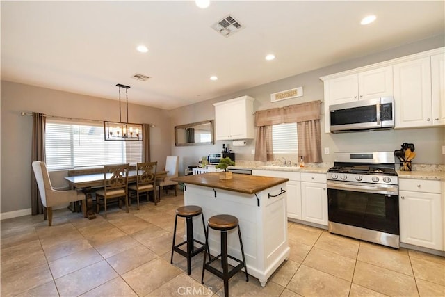 kitchen with pendant lighting, white cabinets, stainless steel appliances, and a kitchen island