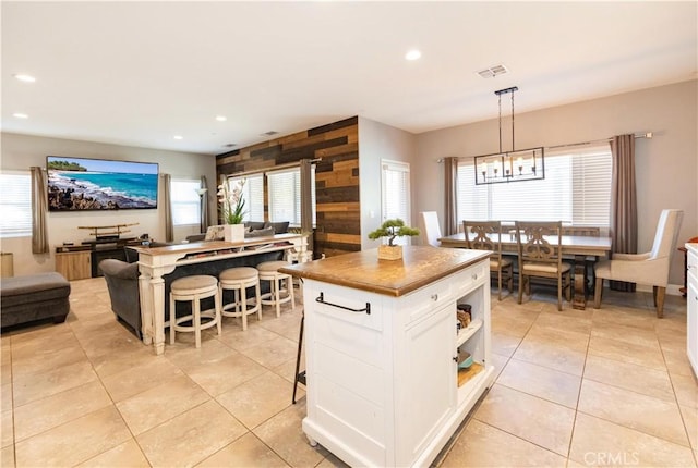 kitchen featuring a center island, white cabinets, a kitchen breakfast bar, hanging light fixtures, and light tile patterned floors