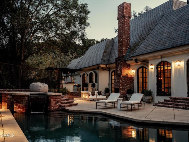 pool at dusk featuring area for grilling and a patio area