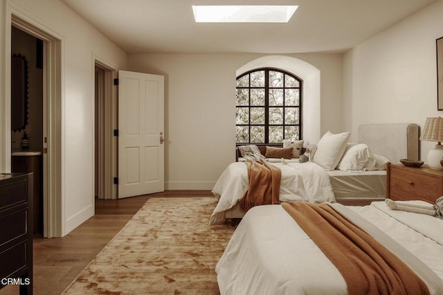 bedroom with a skylight and hardwood / wood-style floors