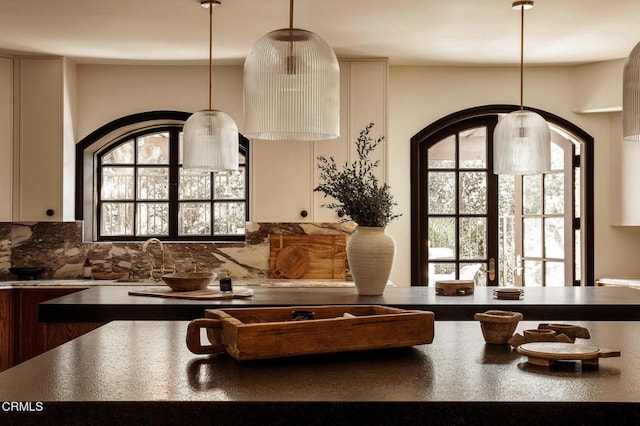 kitchen with backsplash, decorative light fixtures, a wealth of natural light, and sink