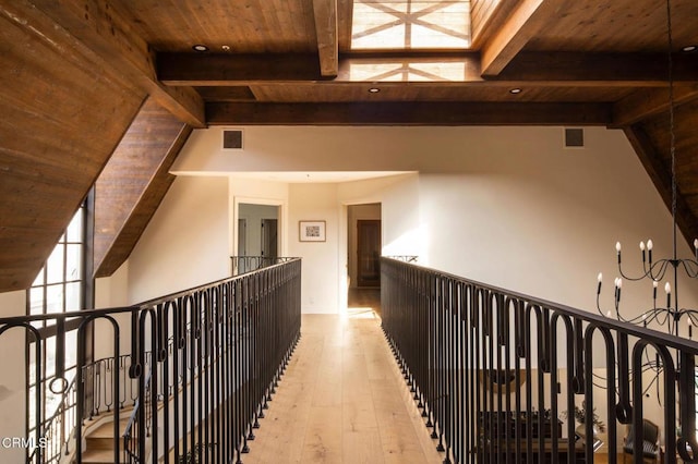 hallway featuring light wood-type flooring, lofted ceiling with beams, and wooden ceiling