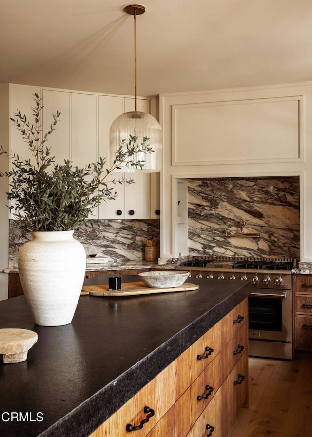 kitchen with hanging light fixtures, tasteful backsplash, stainless steel range, and dark wood-type flooring