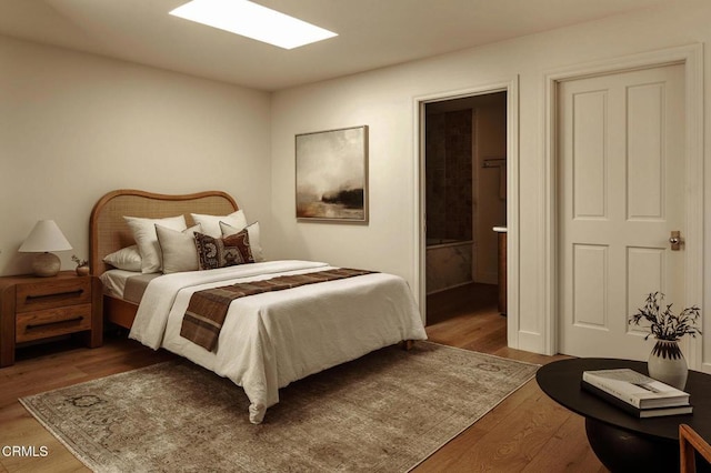 bedroom with ensuite bath and hardwood / wood-style floors