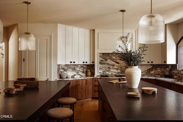 kitchen featuring decorative backsplash, sink, a kitchen island, and hanging light fixtures