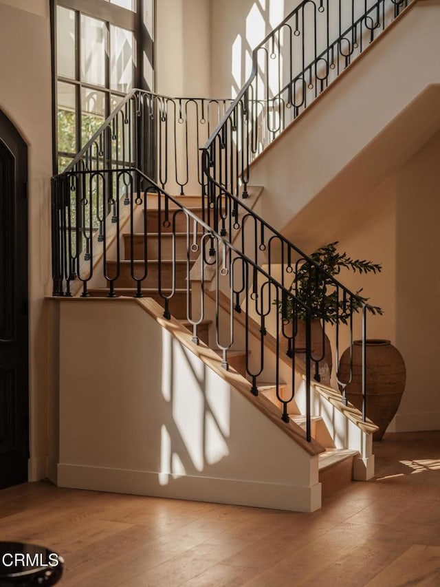 stairs featuring hardwood / wood-style flooring and a high ceiling