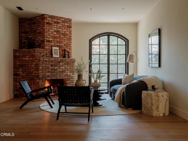 living area featuring wood-type flooring and a brick fireplace