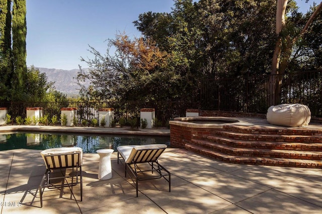 view of patio / terrace with a mountain view and a pool with hot tub