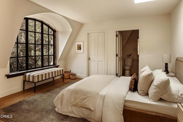 bedroom featuring dark hardwood / wood-style flooring and connected bathroom