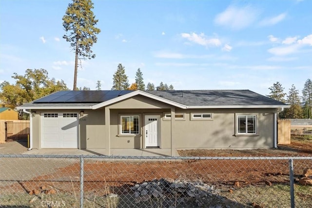 ranch-style home with a garage and solar panels