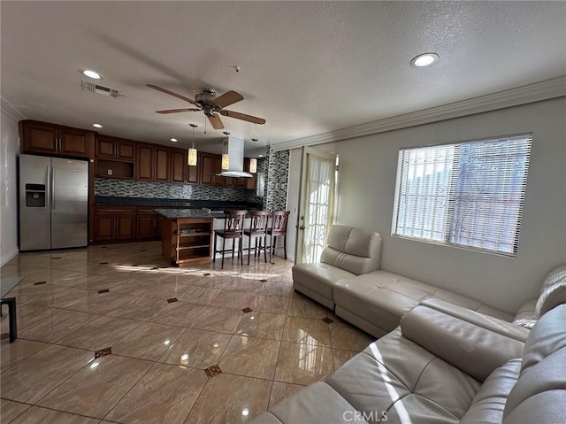 tiled living room featuring crown molding, ceiling fan, and a textured ceiling