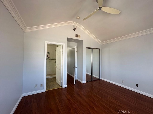 unfurnished bedroom with lofted ceiling, dark wood-type flooring, crown molding, ceiling fan, and a closet