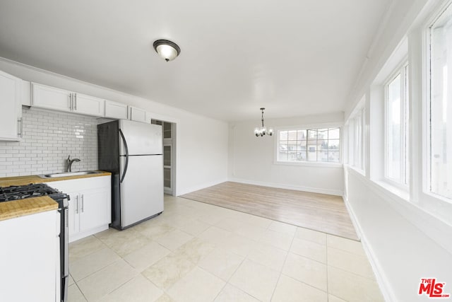 kitchen with white cabinetry, an inviting chandelier, tasteful backsplash, light hardwood / wood-style floors, and fridge