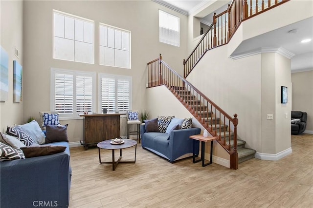 living room featuring a high ceiling, light hardwood / wood-style floors, and ornamental molding