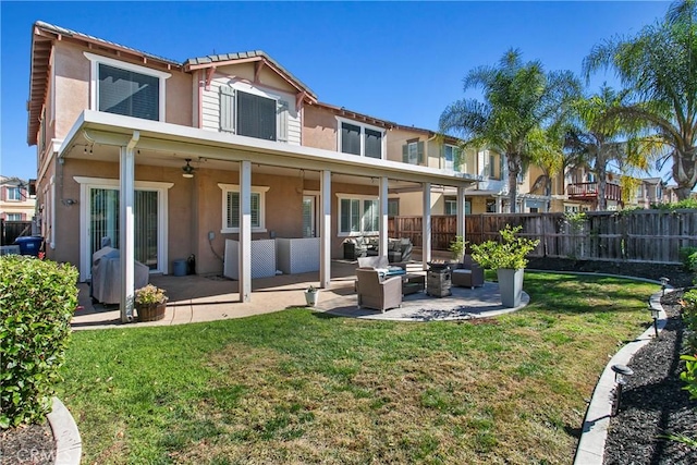 back of property with an outdoor living space, ceiling fan, a yard, and a patio