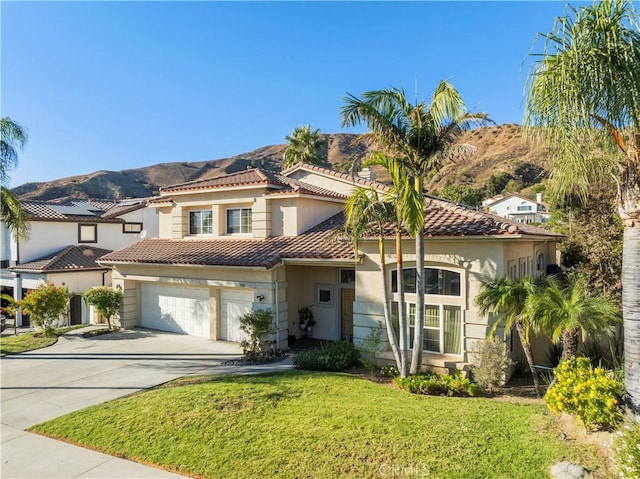 mediterranean / spanish home featuring a mountain view, a garage, and a front yard