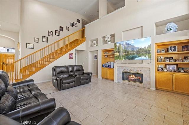 tiled living room with a tiled fireplace, built in features, and high vaulted ceiling