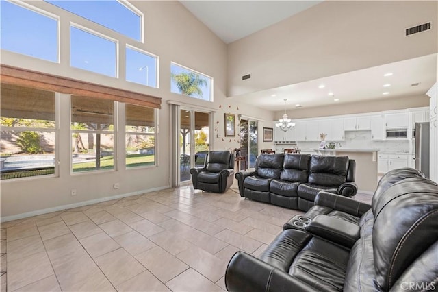 living room with a notable chandelier, plenty of natural light, light tile patterned floors, and high vaulted ceiling