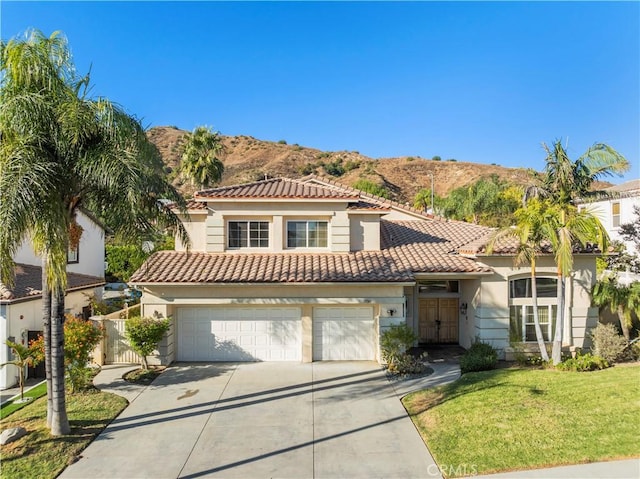 mediterranean / spanish house with a mountain view, a garage, and a front lawn