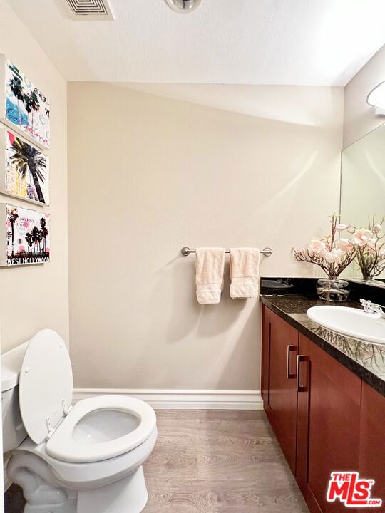 bathroom with hardwood / wood-style floors, vanity, and toilet