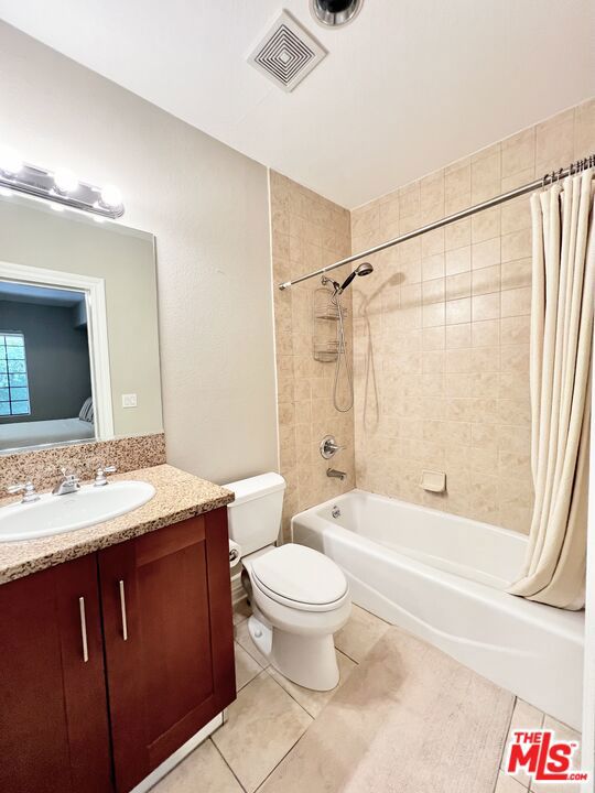 full bathroom with tile patterned flooring, shower / bath combo, toilet, and vanity