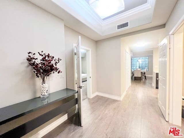 hall with a tray ceiling and light hardwood / wood-style flooring