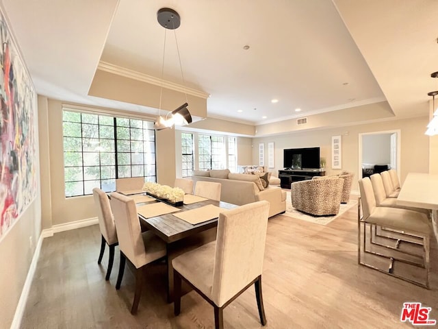 dining room featuring light wood-type flooring, crown molding, and a tray ceiling