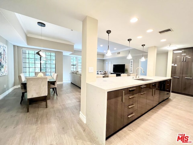 kitchen with crown molding, sink, dark brown cabinets, and light wood-type flooring