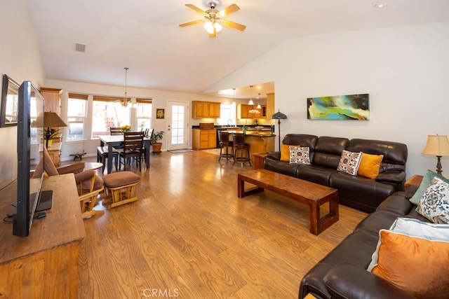 living room featuring ceiling fan with notable chandelier, light hardwood / wood-style floors, lofted ceiling, and sink