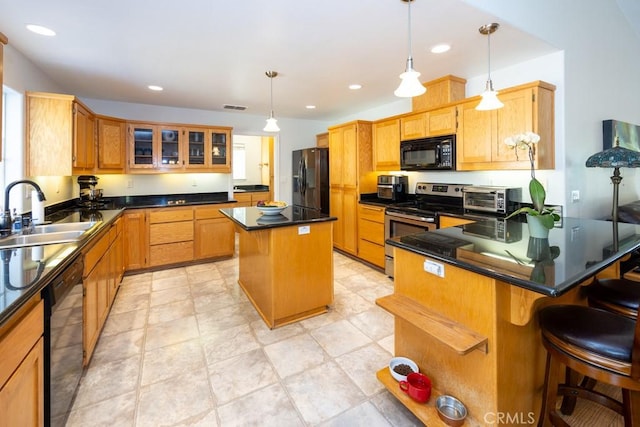 kitchen with a breakfast bar, black appliances, sink, decorative light fixtures, and a kitchen island