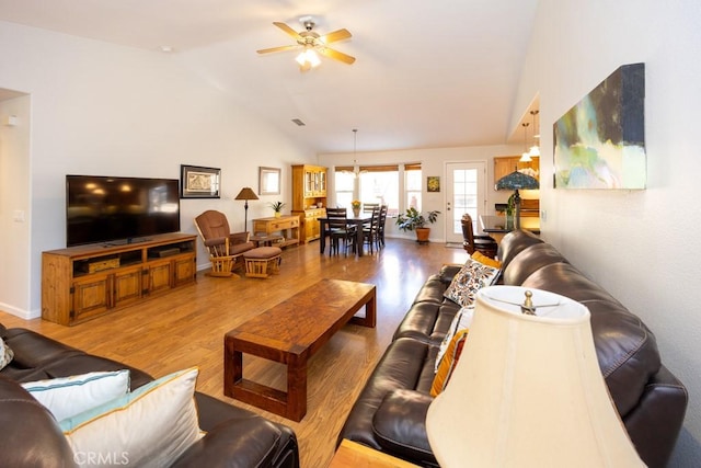 living room with hardwood / wood-style flooring, ceiling fan, and high vaulted ceiling