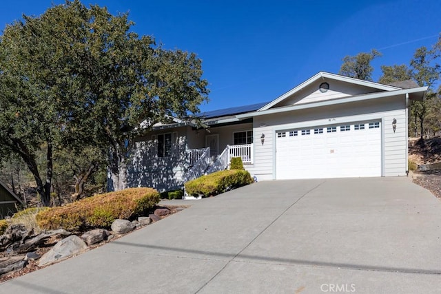 ranch-style house featuring solar panels, a porch, and a garage