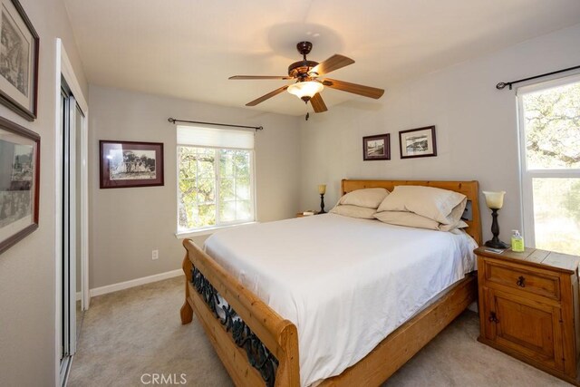 bedroom featuring ceiling fan, a closet, light carpet, and multiple windows