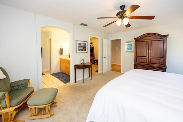 bedroom featuring ensuite bathroom, ceiling fan, and light carpet