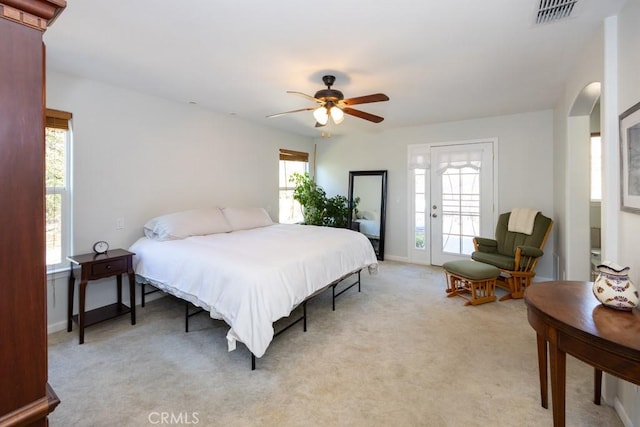 bedroom featuring access to exterior, light carpet, multiple windows, and ceiling fan