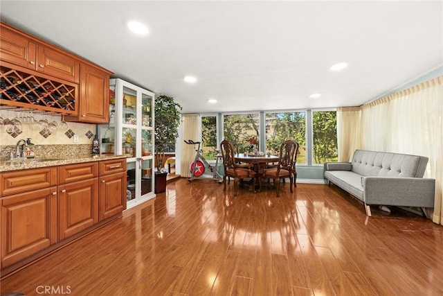 kitchen featuring sink, tasteful backsplash, light stone counters, expansive windows, and wood-type flooring