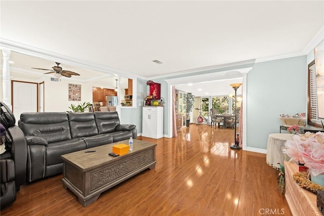 living room featuring wood-type flooring, ornate columns, ceiling fan, and ornamental molding