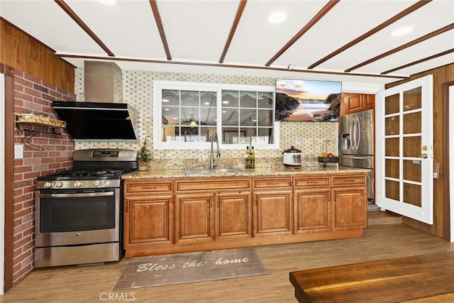 kitchen featuring sink, stainless steel appliances, light stone counters, decorative backsplash, and light wood-type flooring