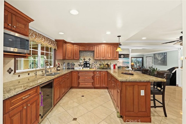 kitchen featuring sink, wine cooler, decorative light fixtures, a breakfast bar, and ornamental molding