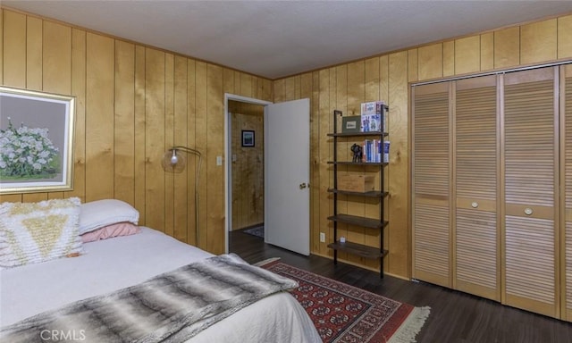 bedroom with wood walls, a closet, and dark hardwood / wood-style floors