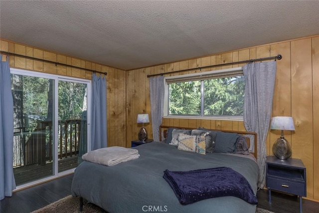 bedroom with access to exterior, wood walls, dark hardwood / wood-style flooring, and multiple windows