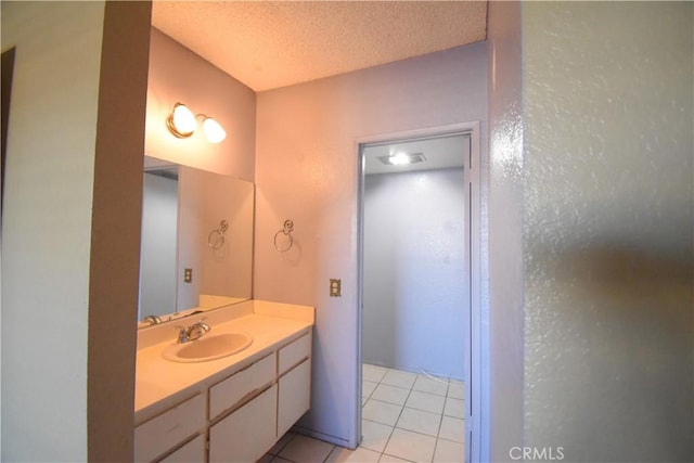 bathroom with tile patterned flooring, a textured ceiling, and vanity