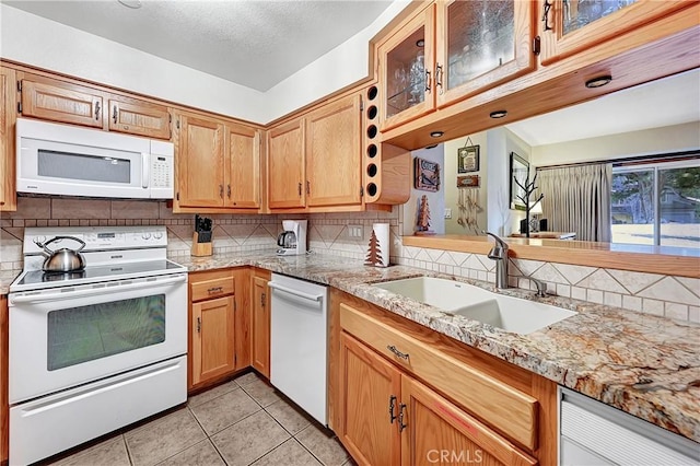 kitchen with backsplash, sink, white appliances, light tile patterned floors, and light stone counters