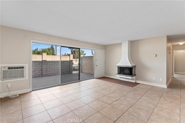 unfurnished living room with light tile patterned flooring, baseboards, and a wall mounted AC