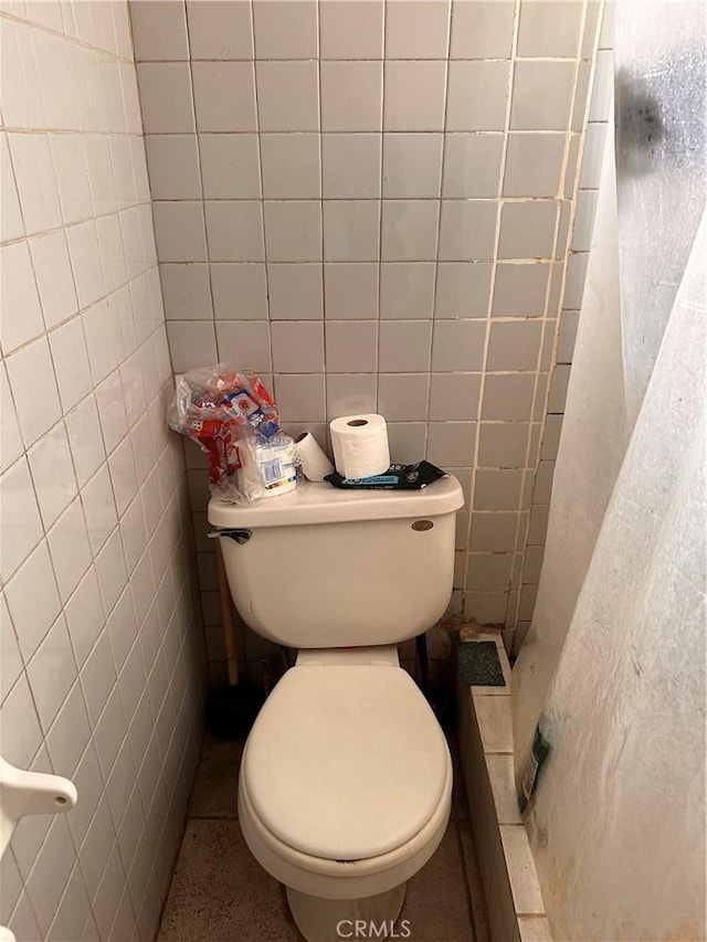 bathroom with toilet and tile walls