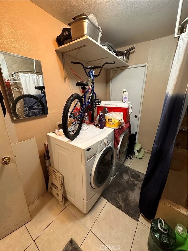 laundry room with washer and clothes dryer, light tile patterned flooring, and a textured ceiling