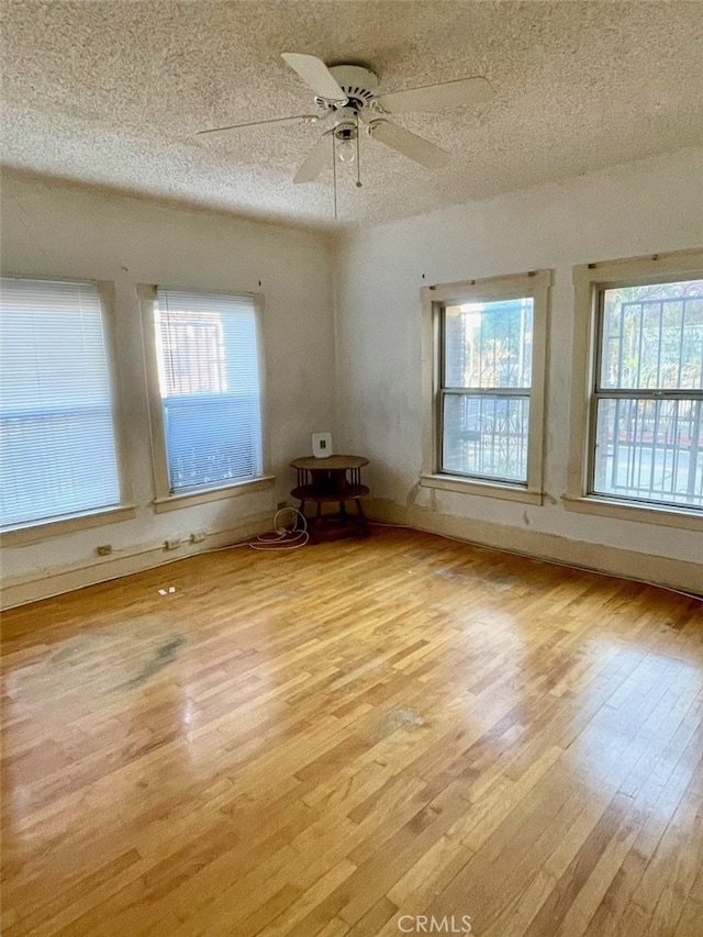 empty room with light hardwood / wood-style flooring, plenty of natural light, and ceiling fan