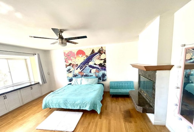 bedroom with ceiling fan, light hardwood / wood-style flooring, and a tile fireplace