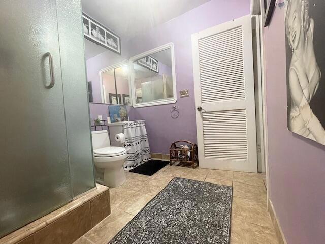 bathroom featuring tile patterned floors, toilet, and walk in shower